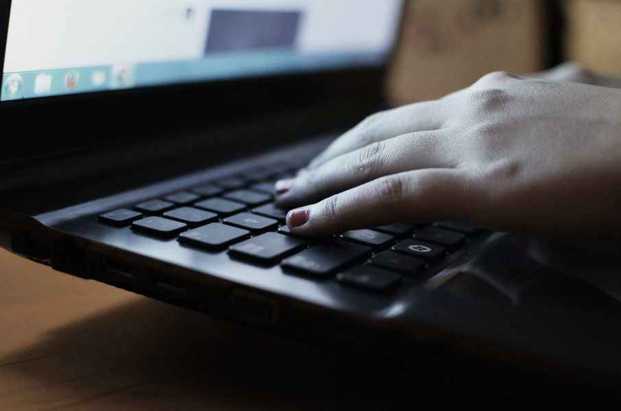 a hand rests on the keyboard of an open laptop
